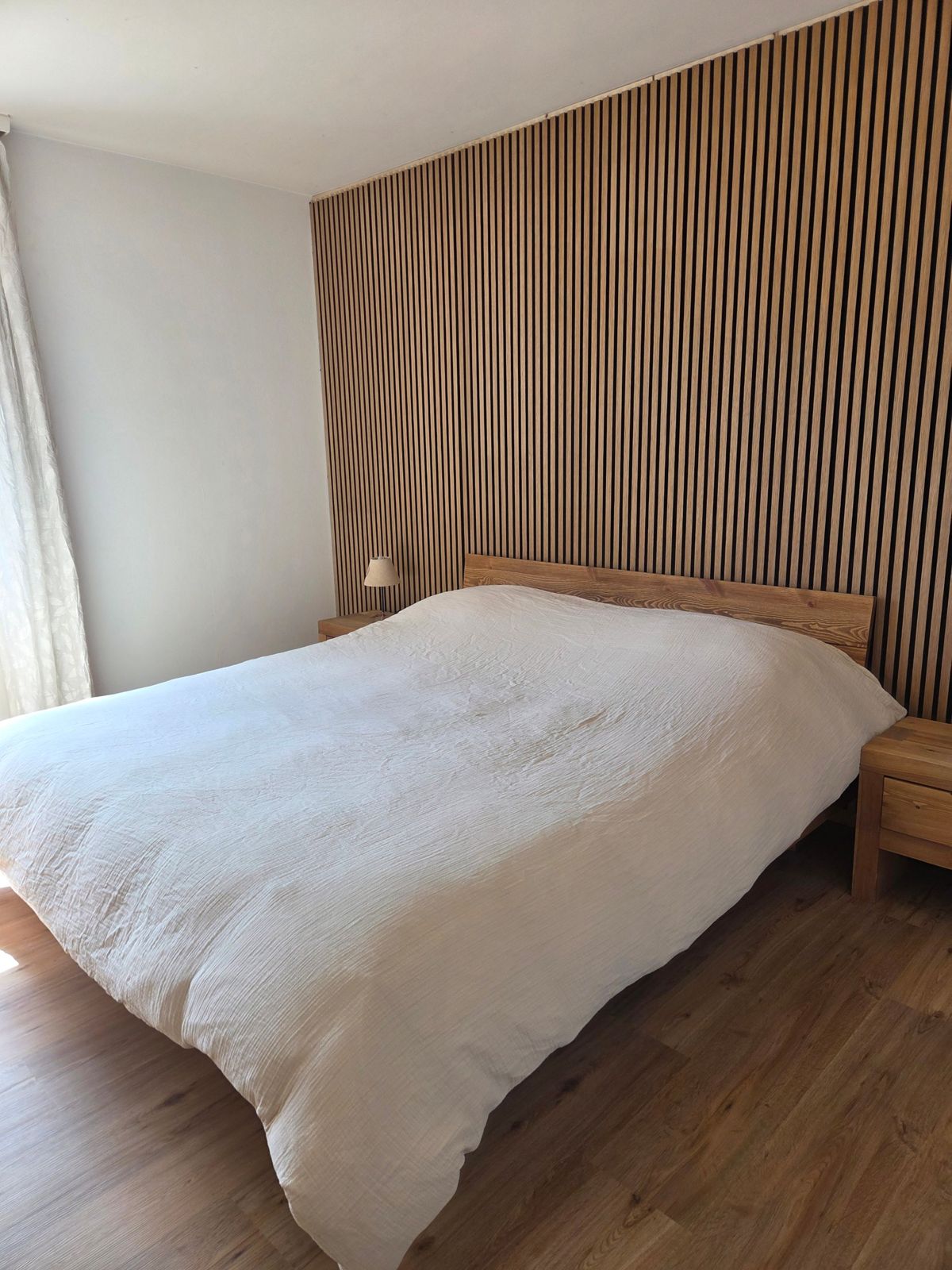 Chambre parentale avec grand lit et mur en lames bois